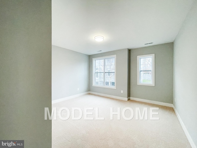 carpeted spare room with visible vents and baseboards