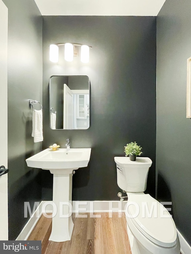 bathroom featuring toilet, wood finished floors, and baseboards