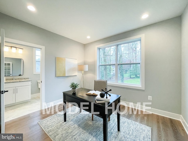 office area with baseboards, light wood finished floors, and recessed lighting
