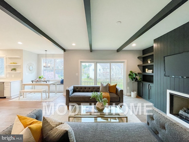 living room with built in features, baseboards, a fireplace, beam ceiling, and light wood-style flooring
