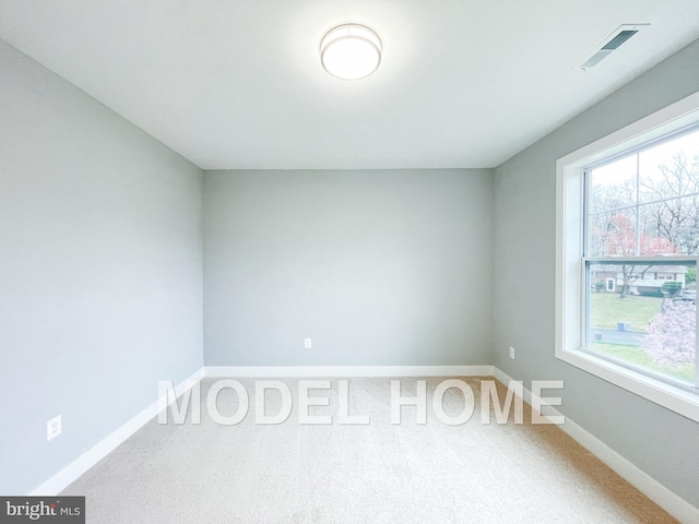 carpeted empty room with plenty of natural light, visible vents, and baseboards