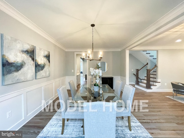dining room featuring crown molding, wood finished floors, an inviting chandelier, and stairway