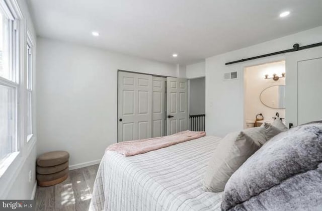 bedroom featuring a closet, wood-type flooring, and a barn door