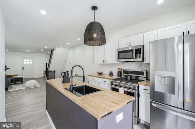 kitchen featuring a center island with sink, pendant lighting, white cabinets, and stainless steel appliances