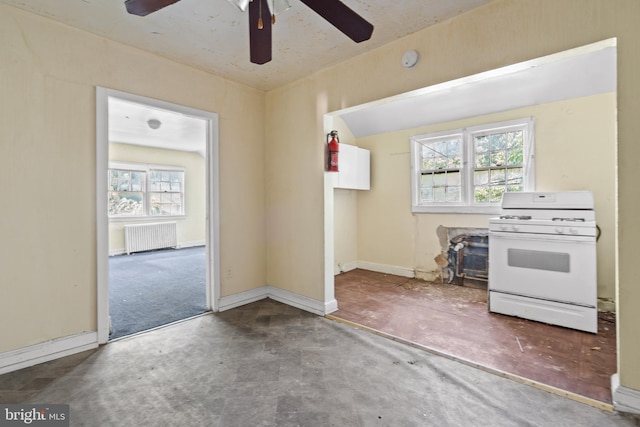 kitchen featuring a healthy amount of sunlight, ceiling fan, radiator, and white range with gas stovetop