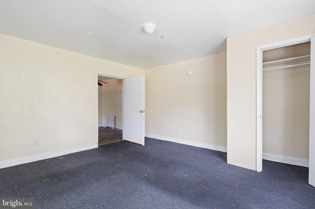 unfurnished bedroom with dark carpet and a closet