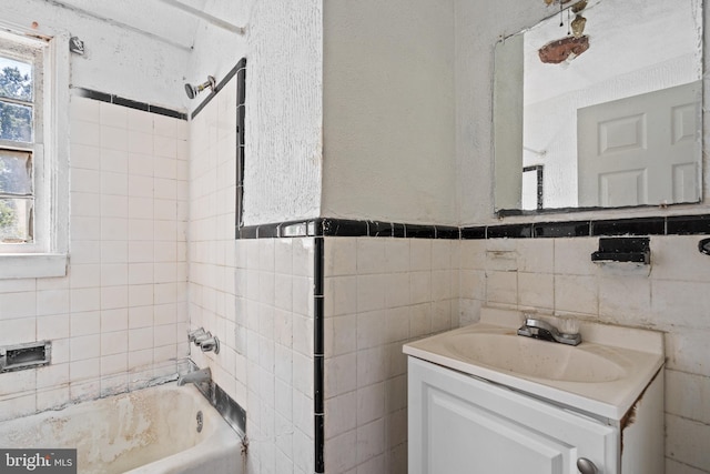 bathroom with tiled shower / bath combo, vanity, and tile walls