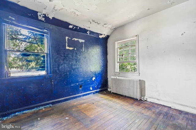 unfurnished room with radiator, vaulted ceiling, and wood-type flooring