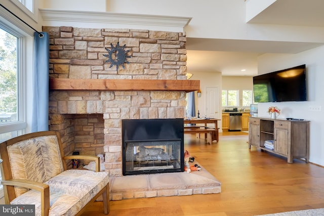 sitting room featuring a fireplace, plenty of natural light, wood-type flooring, and crown molding