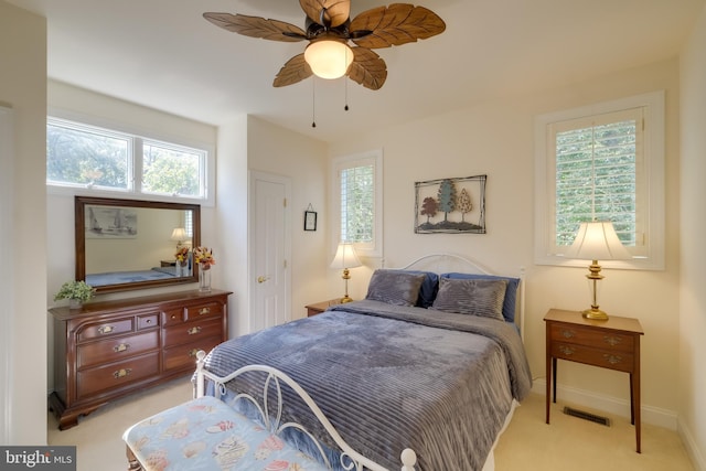 carpeted bedroom featuring multiple windows and ceiling fan