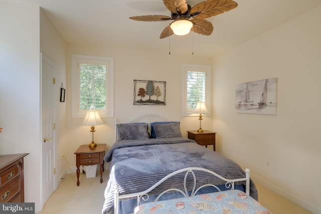 bedroom with ceiling fan, light colored carpet, and multiple windows