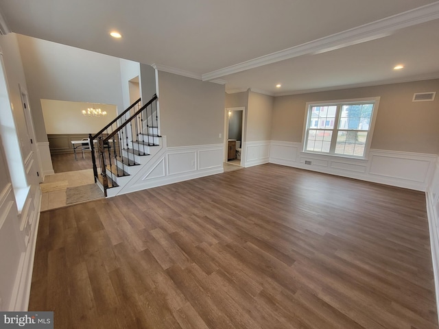 unfurnished living room with crown molding, wood-type flooring, and a notable chandelier