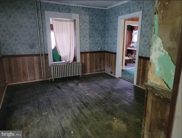 miscellaneous room featuring dark hardwood / wood-style flooring, ornamental molding, wooden walls, and radiator