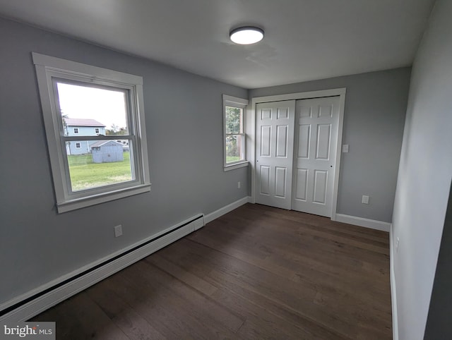 unfurnished bedroom with a closet, a baseboard radiator, and dark hardwood / wood-style floors