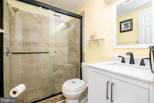 bathroom with vanity, toilet, crown molding, and a shower with door