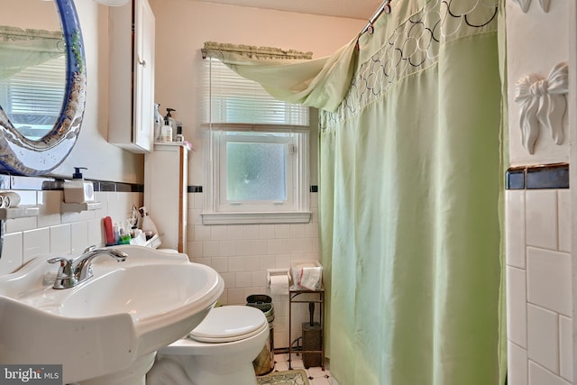 bathroom with tile patterned floors, a sink, curtained shower, tile walls, and toilet