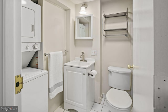 bathroom with toilet, vanity, stacked washer and clothes dryer, and tile patterned flooring