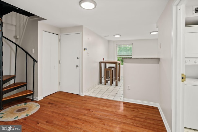 foyer entrance featuring light hardwood / wood-style floors and stacked washer / drying machine