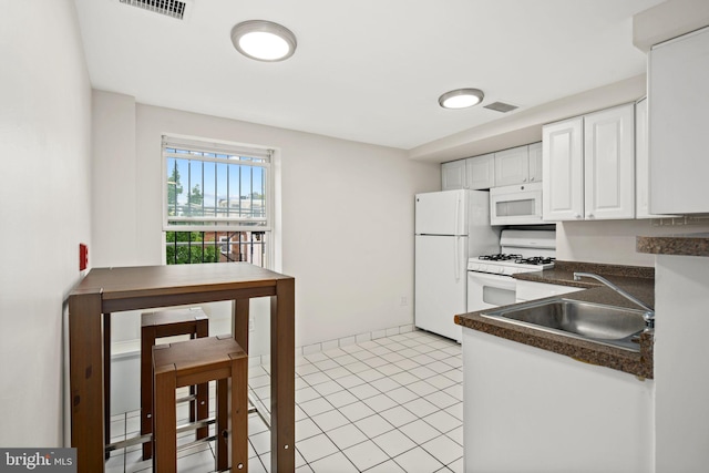 kitchen with light tile patterned flooring, white cabinetry, sink, and white appliances