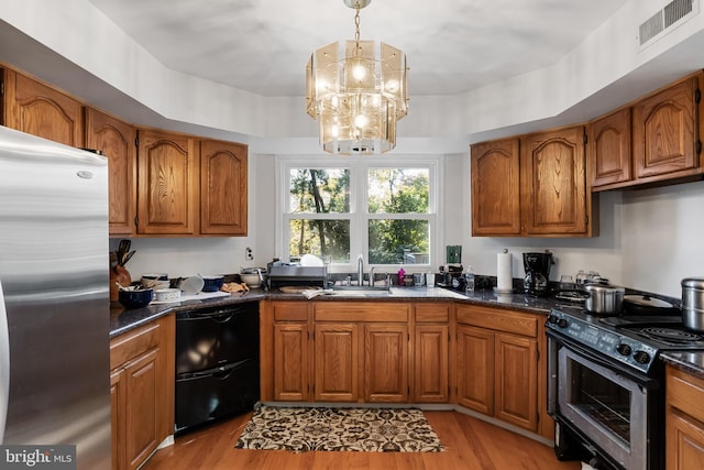 kitchen with black appliances, sink, pendant lighting, light hardwood / wood-style flooring, and a chandelier