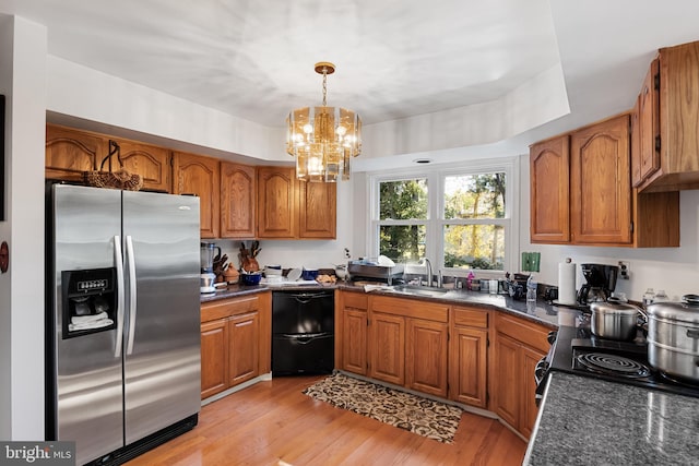 kitchen with appliances with stainless steel finishes, a chandelier, sink, light hardwood / wood-style floors, and decorative light fixtures