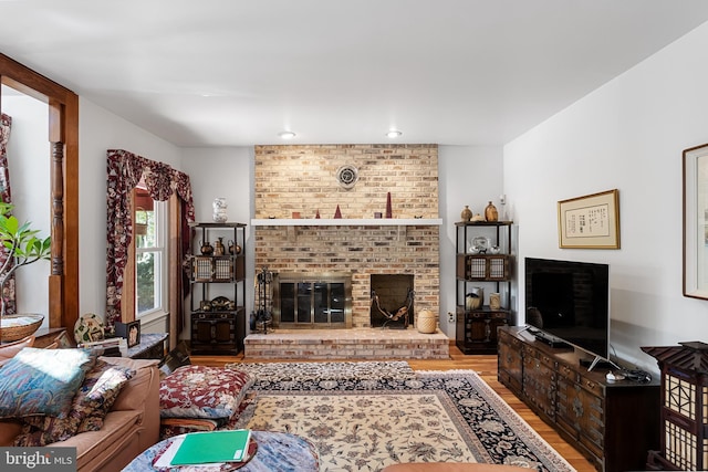 living room with light hardwood / wood-style flooring and a brick fireplace