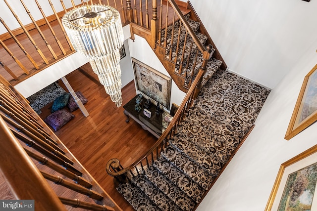 staircase with a notable chandelier and hardwood / wood-style floors