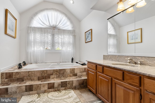 bathroom featuring vaulted ceiling, tiled tub, and a healthy amount of sunlight