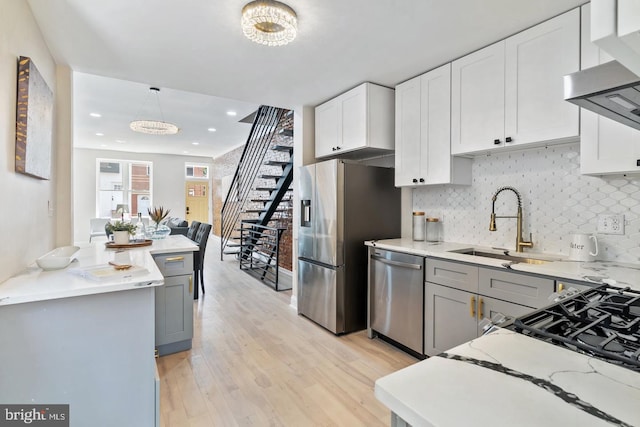 kitchen featuring hanging light fixtures, appliances with stainless steel finishes, white cabinetry, light hardwood / wood-style flooring, and gray cabinets