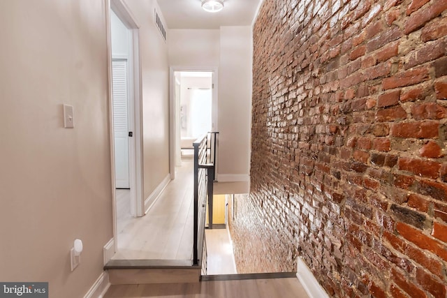 hall with hardwood / wood-style flooring and brick wall