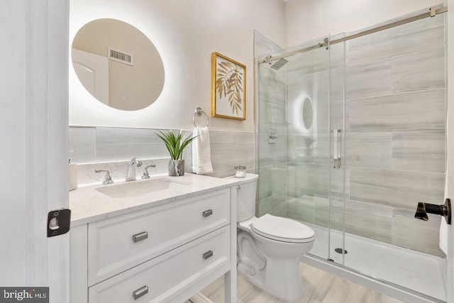 bathroom featuring vanity, toilet, and a shower with door