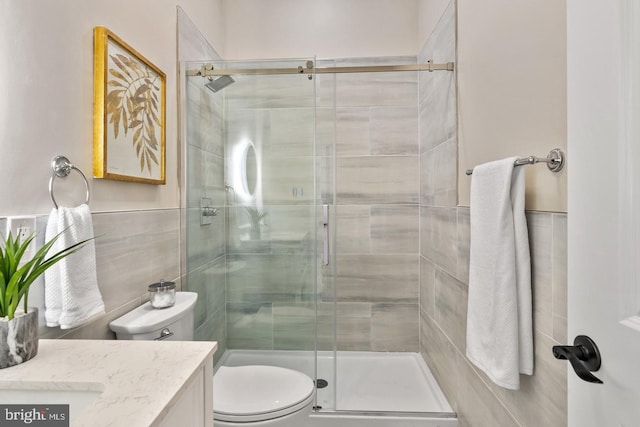 bathroom with a shower with door, vanity, and toilet