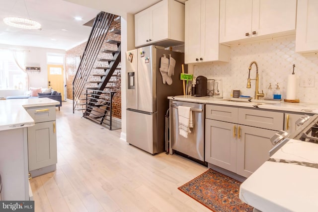 kitchen featuring decorative backsplash, white cabinets, sink, light hardwood / wood-style floors, and stainless steel appliances