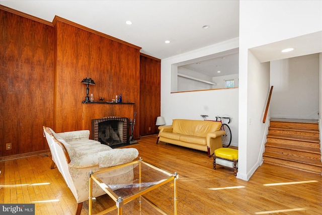 living room with hardwood / wood-style floors, a brick fireplace, and wood walls