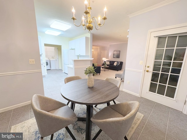 tiled dining room with ornamental molding, separate washer and dryer, and an inviting chandelier