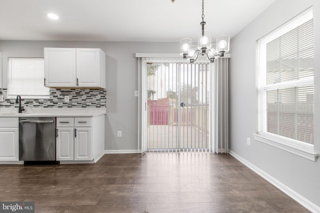 kitchen featuring backsplash, decorative light fixtures, stainless steel dishwasher, white cabinets, and a chandelier