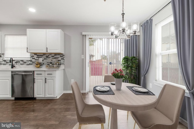 dining room with a wealth of natural light, sink, a notable chandelier, and dark hardwood / wood-style floors