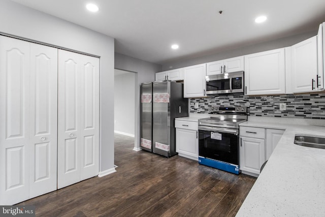 kitchen with decorative backsplash, dark wood-style floors, white cabinetry, and appliances with stainless steel finishes
