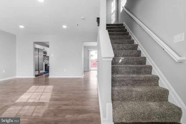 stairs with baseboards, wood finished floors, and recessed lighting