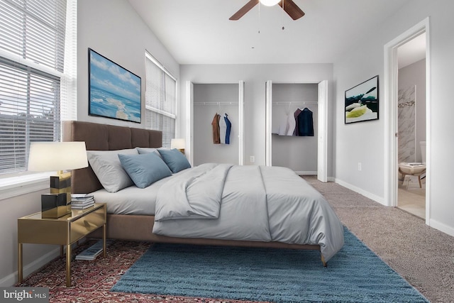 carpeted bedroom with ensuite bath, multiple closets, and ceiling fan