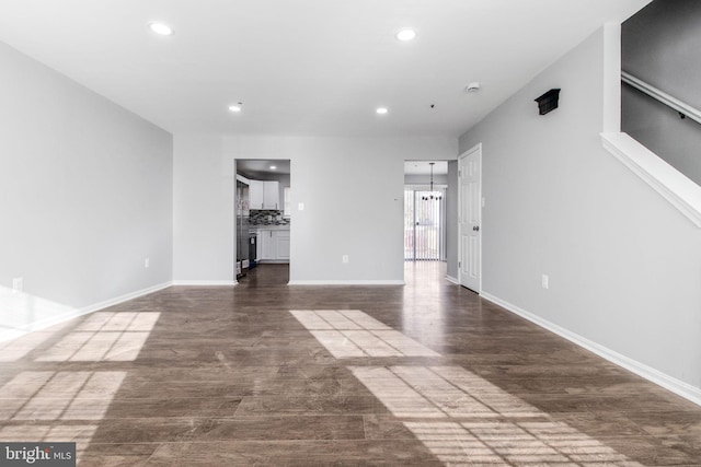 unfurnished living room with an inviting chandelier, dark wood-type flooring, and recessed lighting