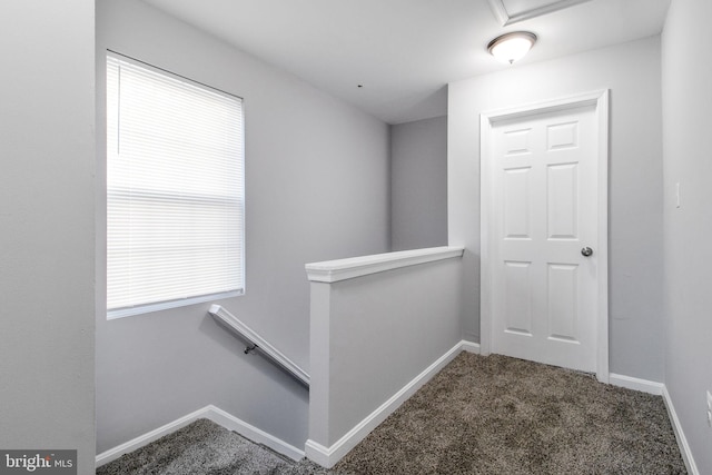 corridor featuring plenty of natural light, carpet floors, baseboards, and an upstairs landing