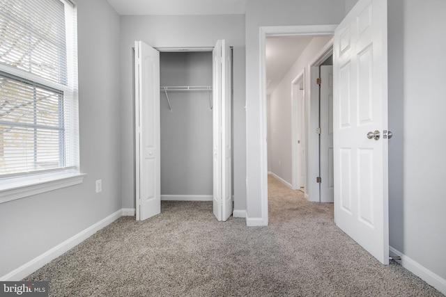 unfurnished bedroom featuring a closet and light colored carpet