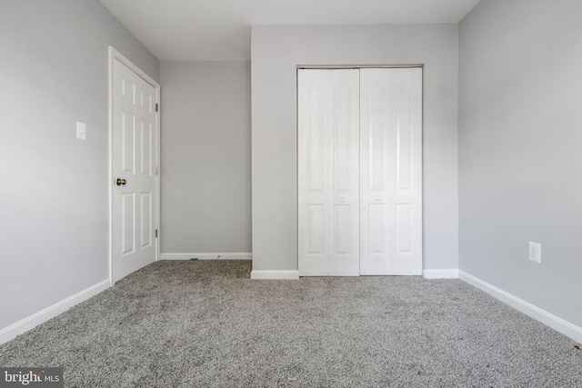 unfurnished bedroom featuring baseboards, carpet, and a closet