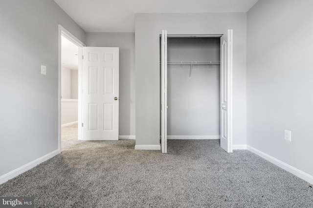 unfurnished bedroom featuring carpet floors, a closet, and baseboards