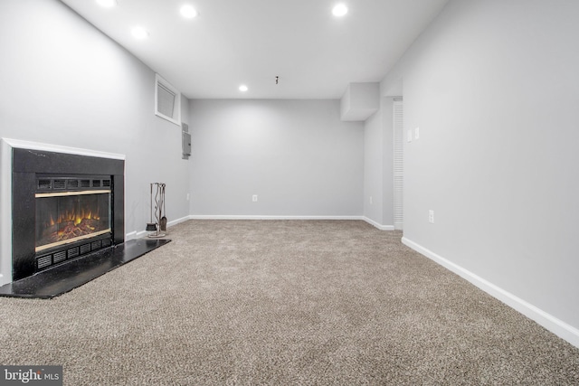 unfurnished living room featuring recessed lighting, a glass covered fireplace, carpet flooring, and baseboards