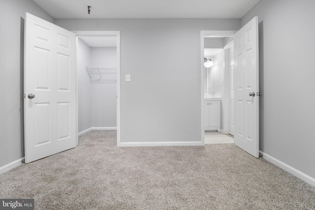 unfurnished bedroom with light carpet, a closet, and a spacious closet