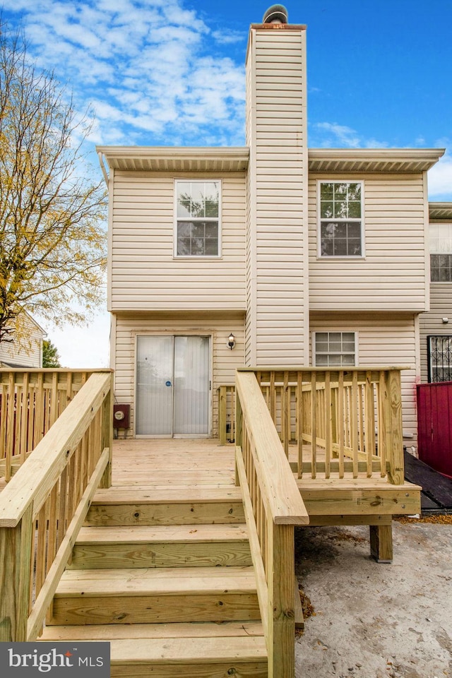 back of house with a wooden deck and a chimney