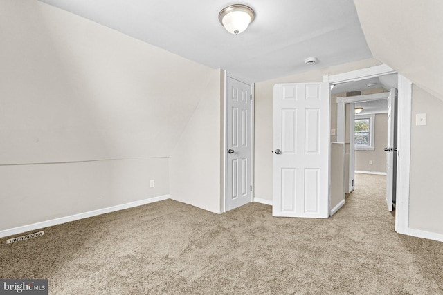 unfurnished bedroom featuring lofted ceiling and light colored carpet