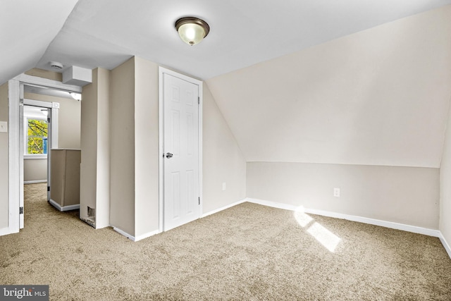 bonus room with vaulted ceiling and light carpet